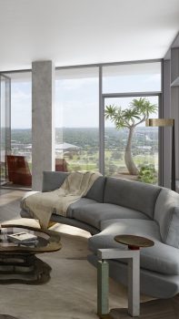 Living room with curved sofa, long table, chairs, kitchen, coffee table, and floor to ceiling glass wall with views of buildings