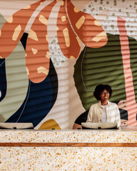 Vibrant reception desk with bold mural backdrop and contemporary design.