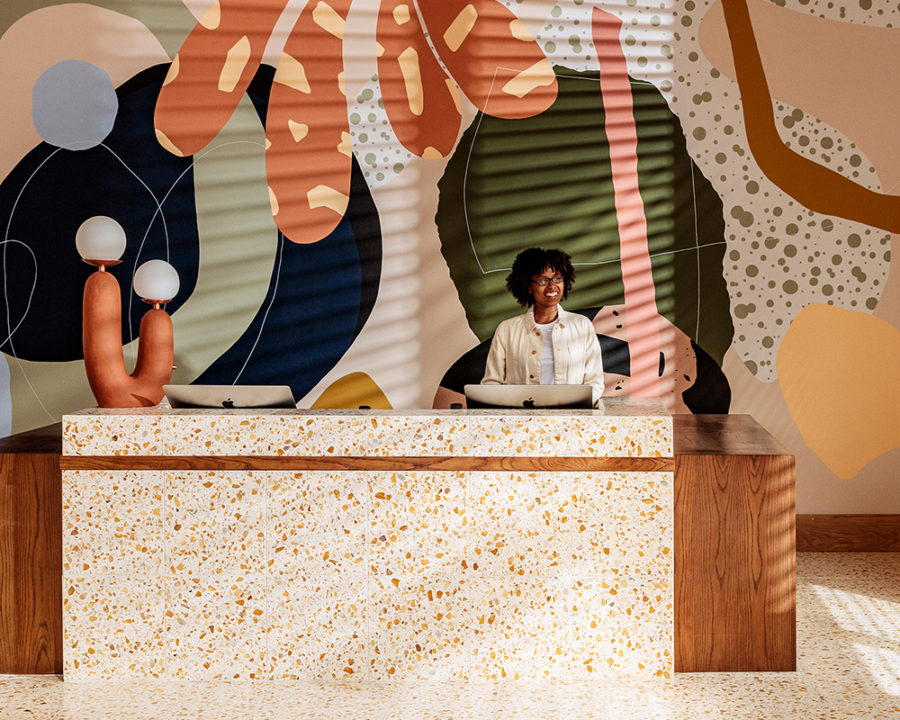 Vibrant reception desk with bold mural backdrop and contemporary design.
