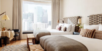 Spacious double guest room with city views, plush beds, and warm contemporary interiors