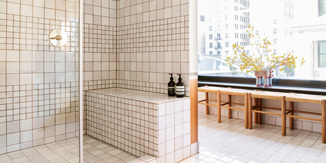 Bright tiled bathroom with walk in shower, bench seating, and large city view windows