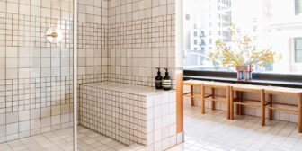 Bright tiled bathroom with walk in shower, bench seating, and large city view windows
