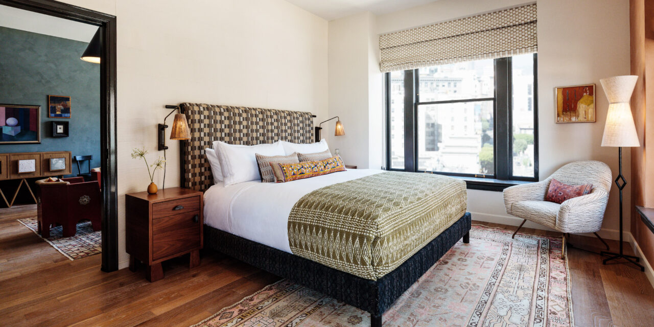 Spacious guest room with city views, patterned textiles, and warm modern furnishings