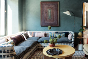 Stylish lounge with patterned sectional sofa, artistic decor, and moody green walls
