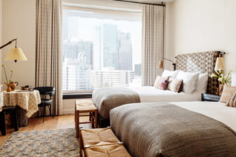Bright double guest room with city skyline views, plush bedding, and contemporary decor