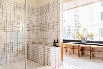 Bright tiled bathroom with walk in shower, bench seating, and city view window nook