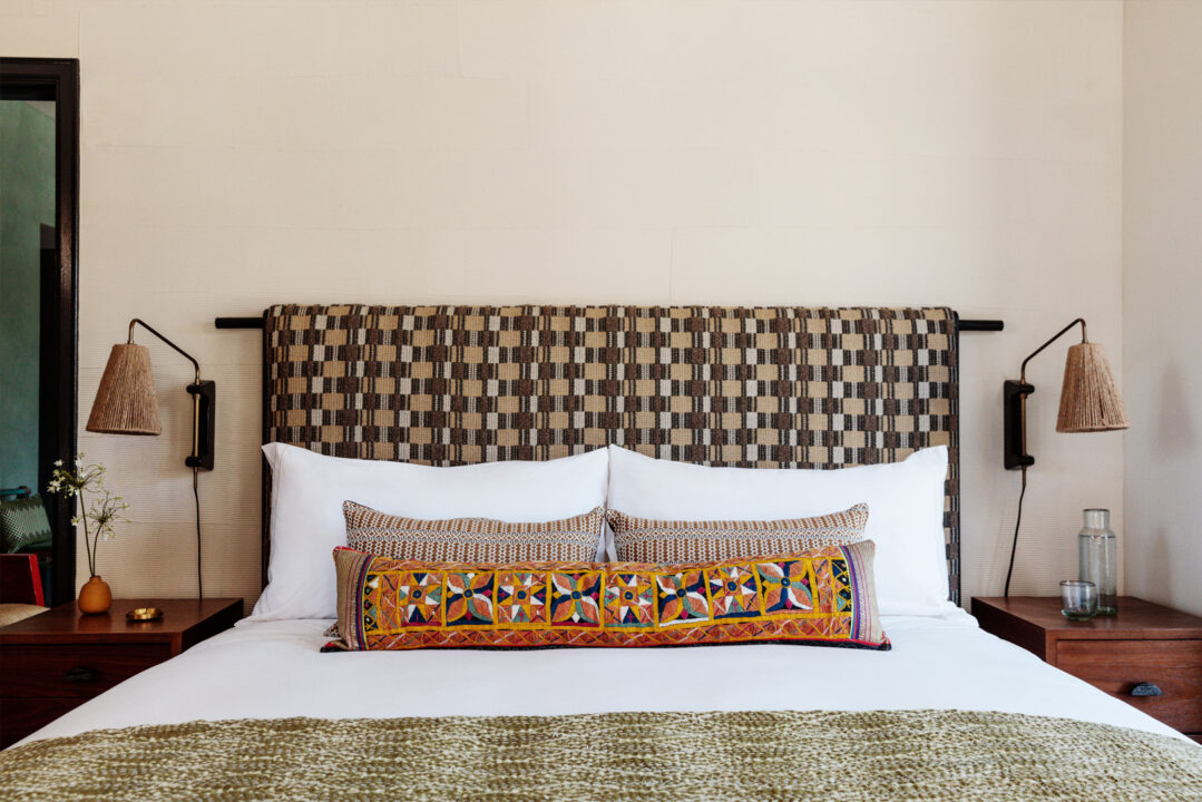 King bed with patterned headboard, artisan accent pillows, and modern bedside lighting