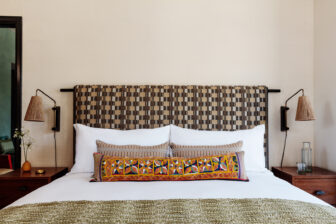 King bed with patterned headboard, artisan accent pillows, and modern bedside lighting