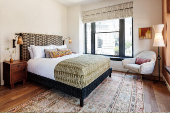 Elegant guest room with king bed, city view windows, and warm modern furnishings