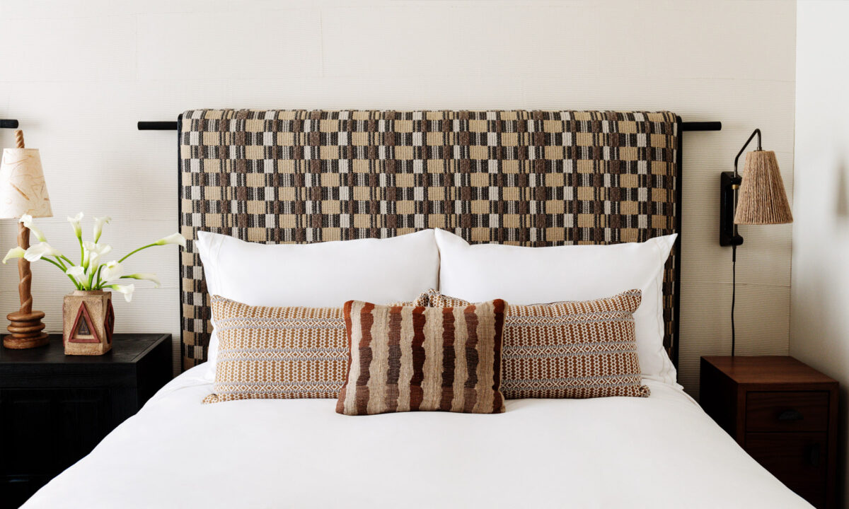 Stylish guest room bed with patterned headboard, layered pillows, and modern bedside lighting