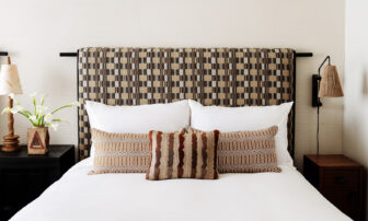 Stylish guest room bed with patterned headboard, layered pillows, and modern bedside lighting