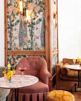 Elegant lounge with plush seating, floral accents, and a bright windowed backdrop