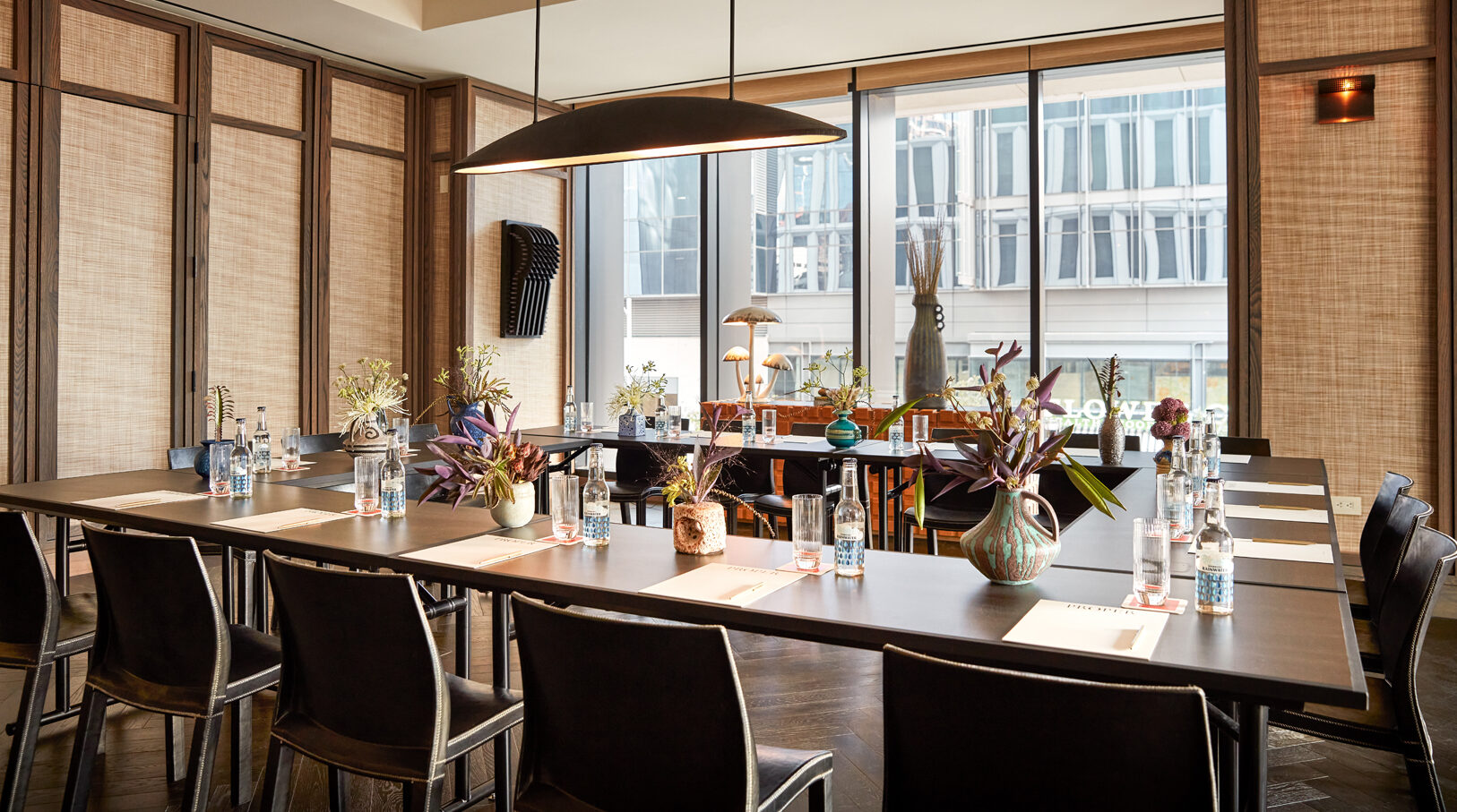 Stylish conference room with U-shaped table setup, floral centerpieces, and large window views