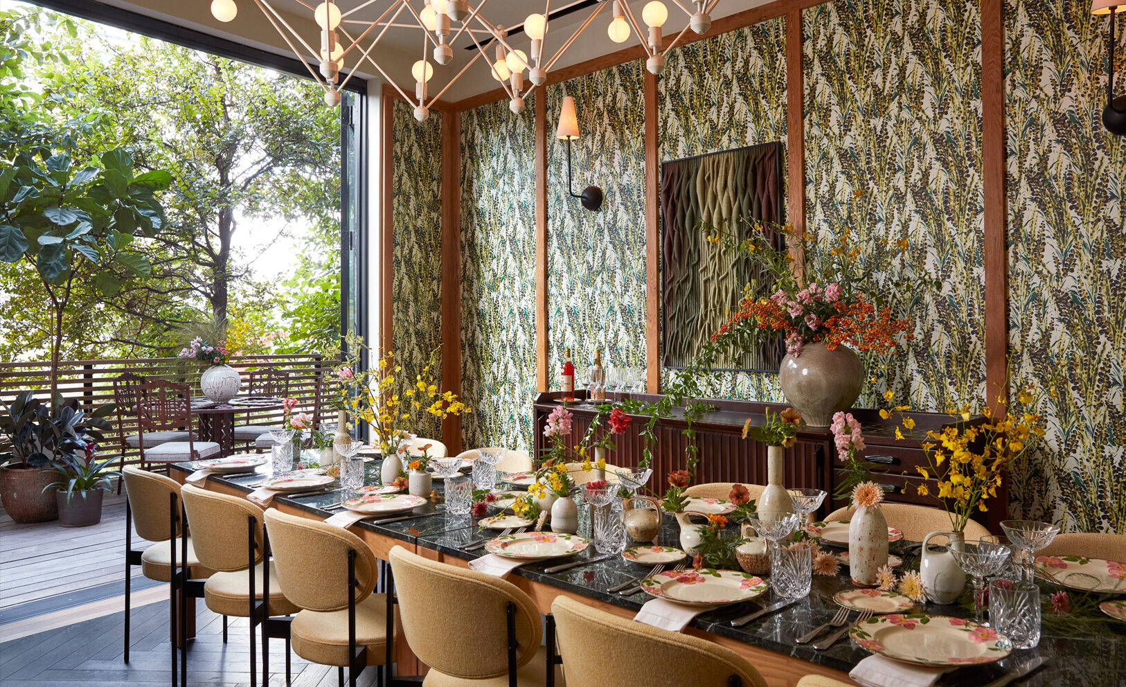 Vibrant private dining space with lush floral decor, patterned walls, and an open terrace view