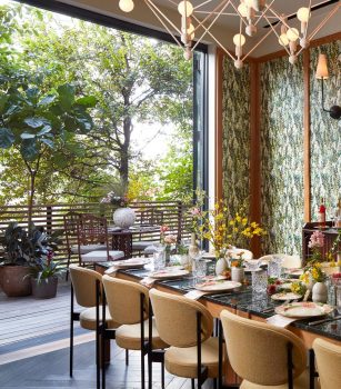 Vibrant private dining space with lush floral decor, patterned walls, and an open terrace view