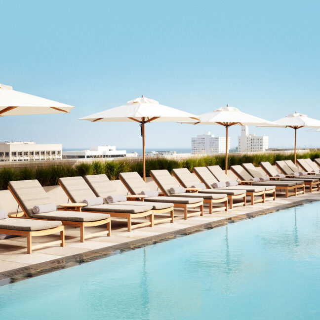 Row of chaise lounge chairs and umbrellas next to Santa monica Proper pool deck