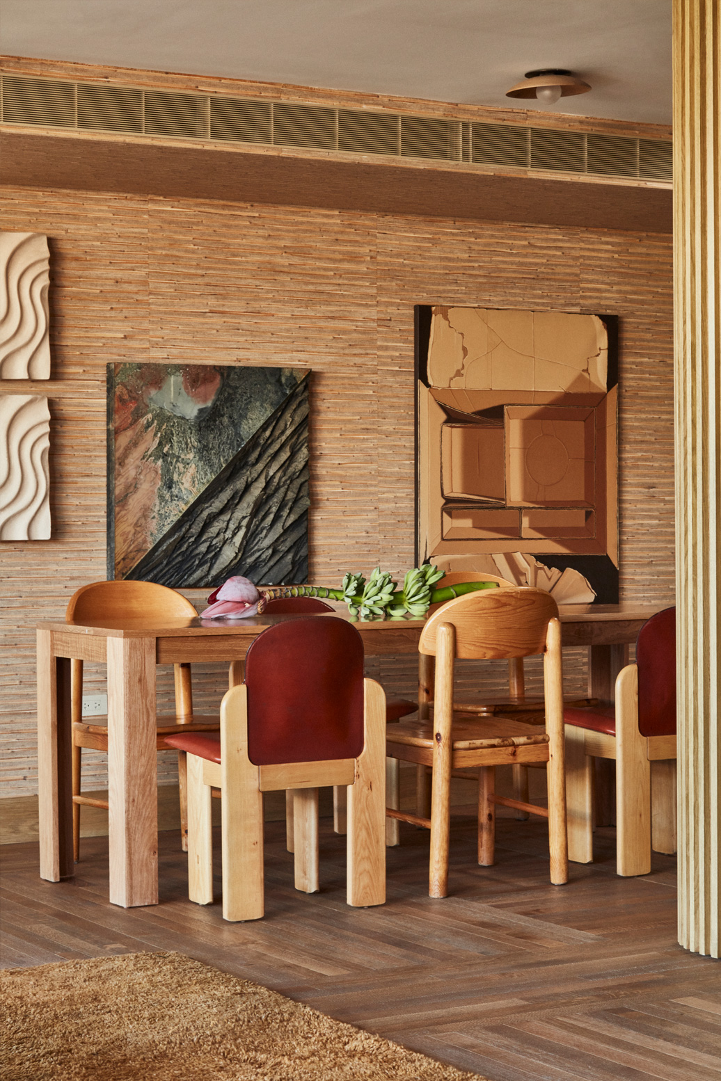 Warm modern dining area with natural wood furniture, artistic decor, and textured wall finishes