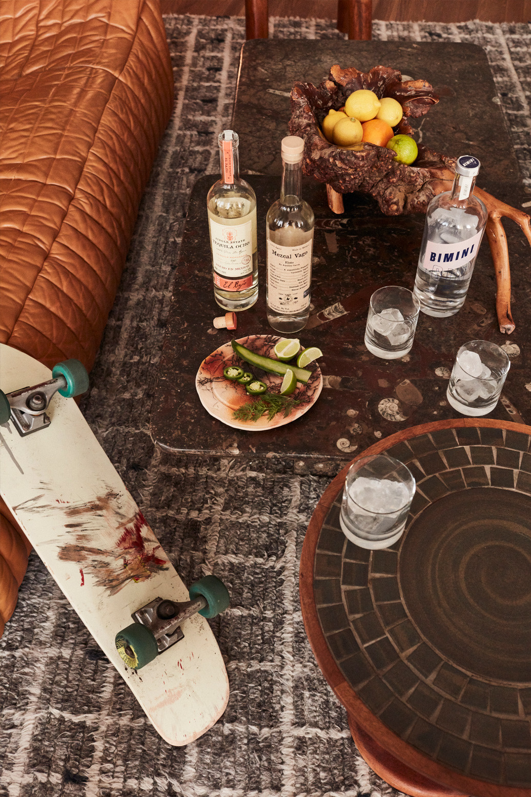 Cocktail setup with tequila bottles, fresh citrus, and skateboard inspired lounge styling