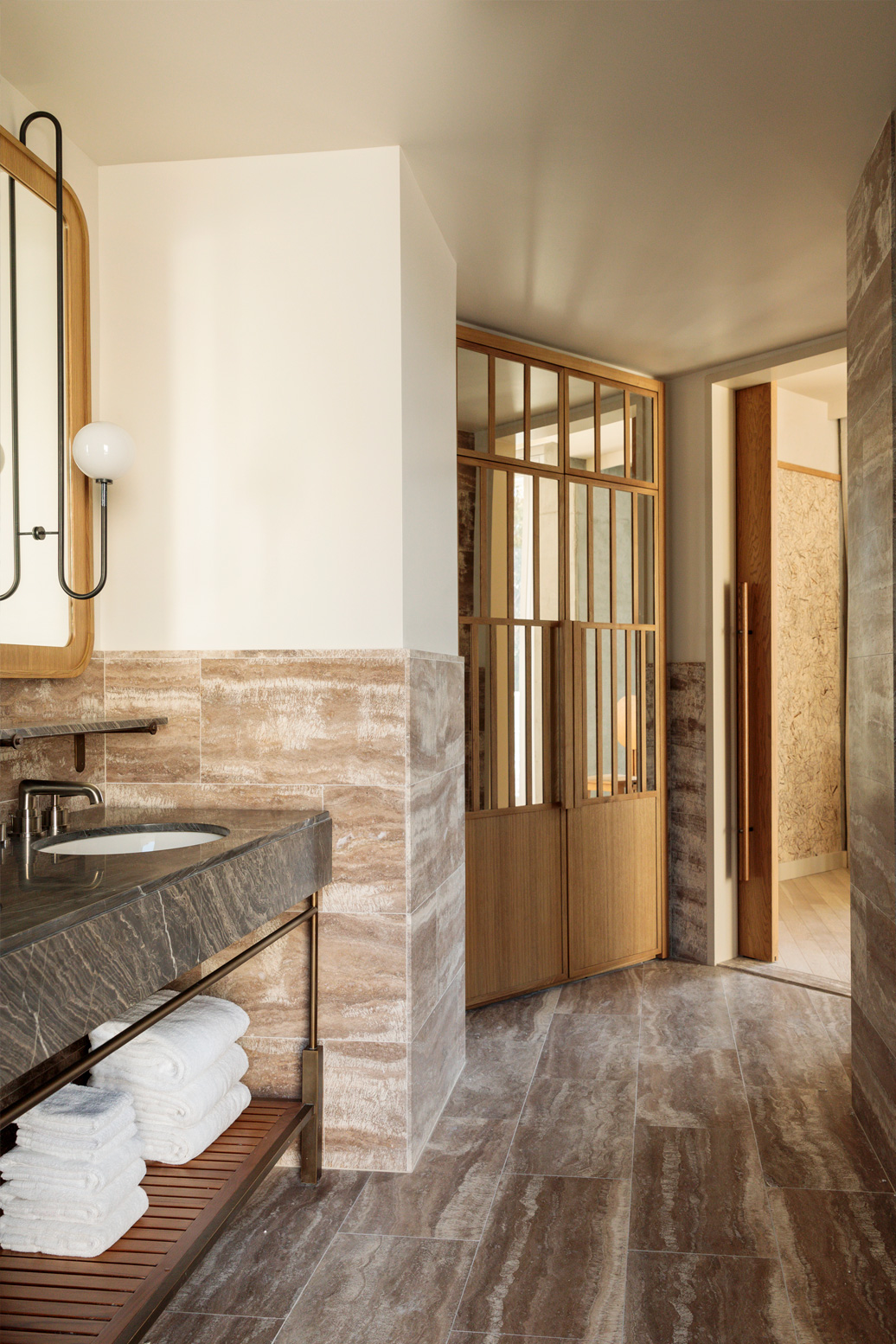 Modern luxury hotel bathroom with stone finishes, marble vanity, and warm wood details