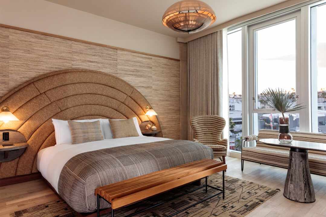 Warm, modern guest room with textured headboard, natural wood accents, and city views.