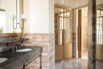 Luxury hotel bathroom with marble vanity, double sinks, walk in shower, and warm wood accents