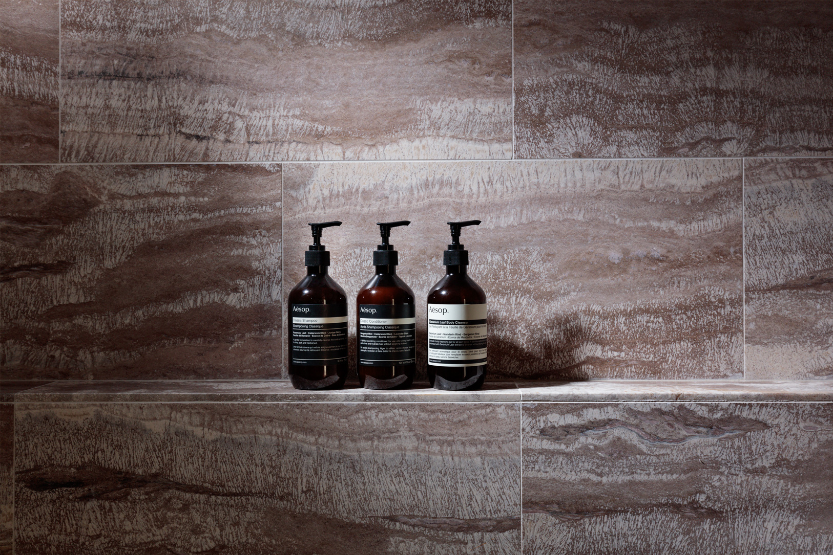 Luxury hotel bathroom amenities displayed on modern stone shower shelf