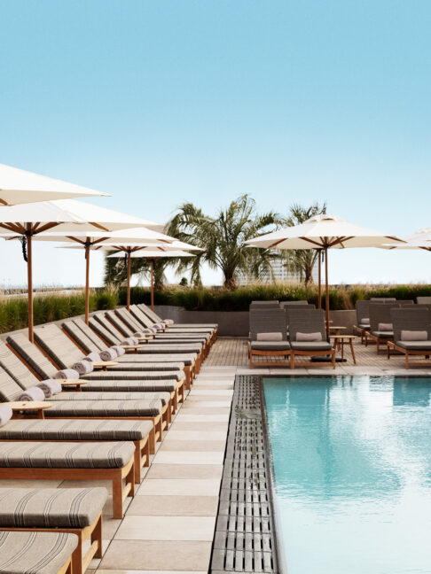 Rooftop pool with lounge chairs and umbrellas overlooking the city
