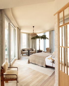 Warm, modern guest room with textured headboard, natural wood accents, and city views.
