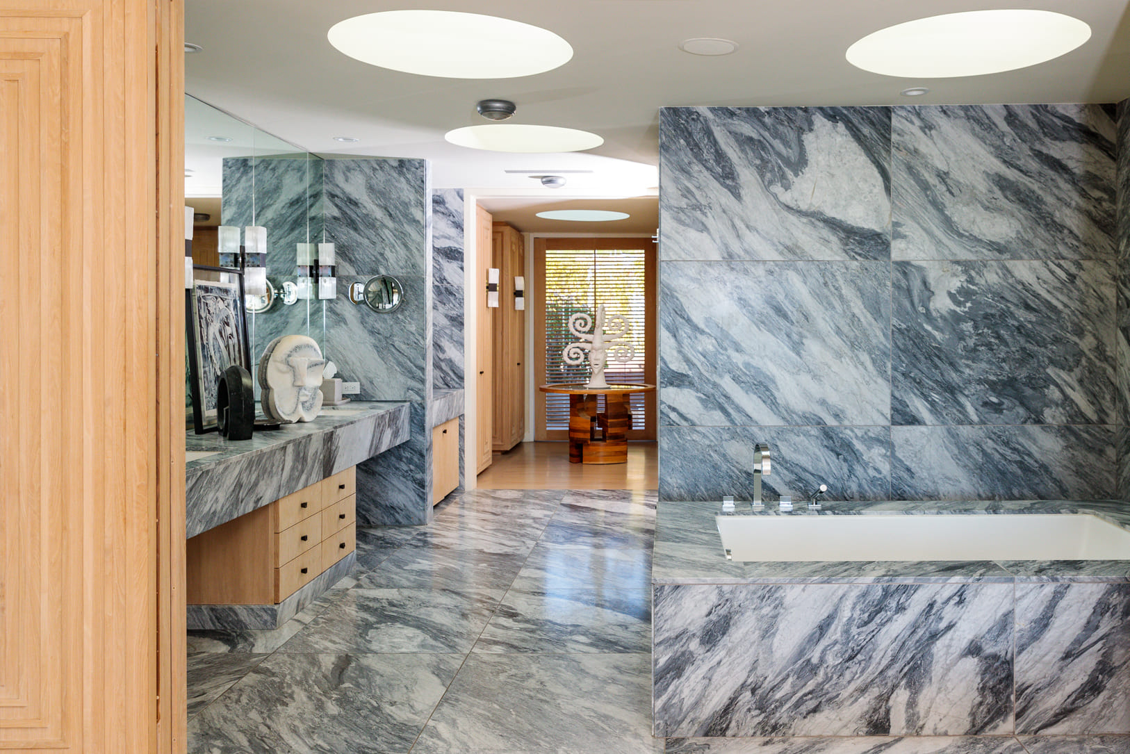 Large bathroom with marble floors and wall, and sink with large mirror