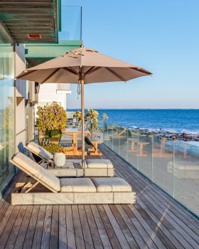 Malibu Beach House beach front terrace with lounge chairs and view of pacific ocean during day time