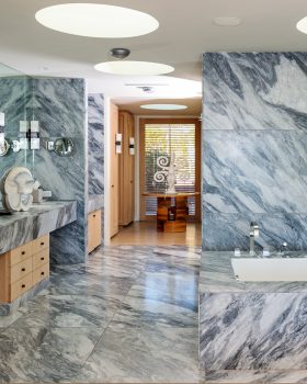 Large bathroom with marble floors and wall, and sink with large mirror