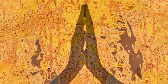 Shadow on wall of hands, palms pressed together