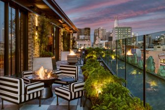 charmaines outdoor rooftop at night with firepits and view of the city skyline