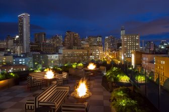 charmaines outdoor rooftop at night with firepits and view of the city skyline