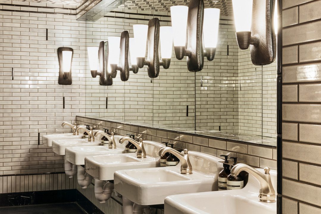 Stylish tiled hotel restroom with modern sinks and decorative lighting