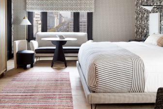 Modern luxury hotel room with plush bedding and panoramic downtown views