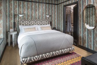 Boutique hotel bedroom with patterned walls, king bed, and modern interior design