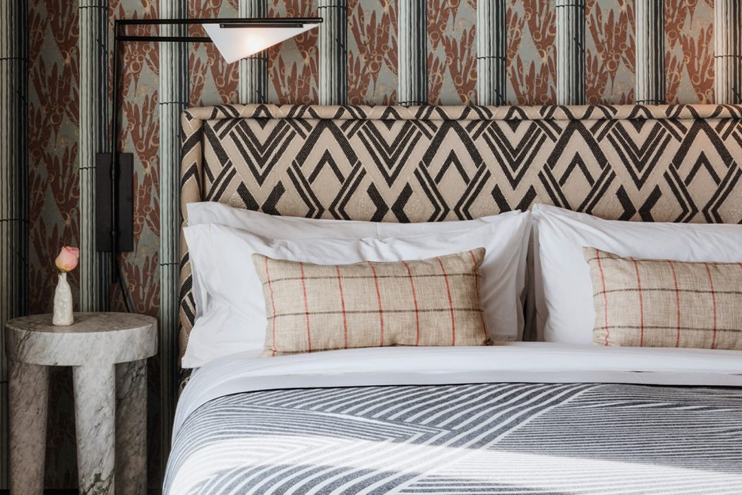 Stylish guest room detail with patterned headboard, layered textiles, and refined accents.