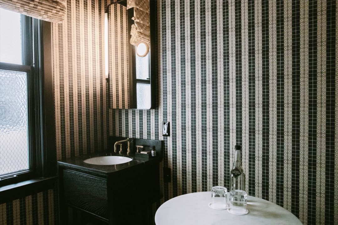 Modern hotel bathroom with striped tile walls and minimalist vanity design