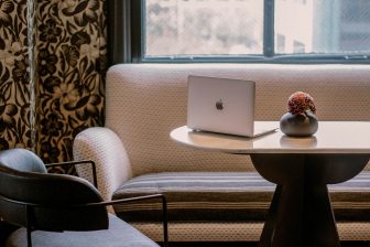Cozy hotel guest room workspace with laptop, lounge seating, and window light