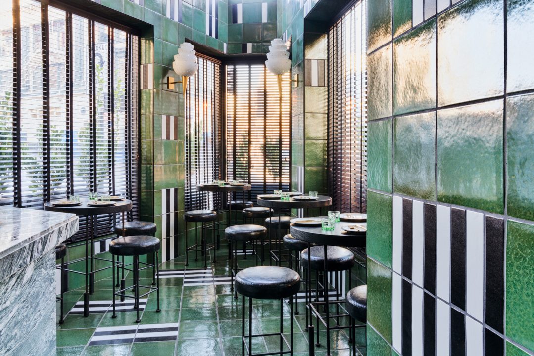 Stylish restaurant seating area with green tiled walls and natural light windows