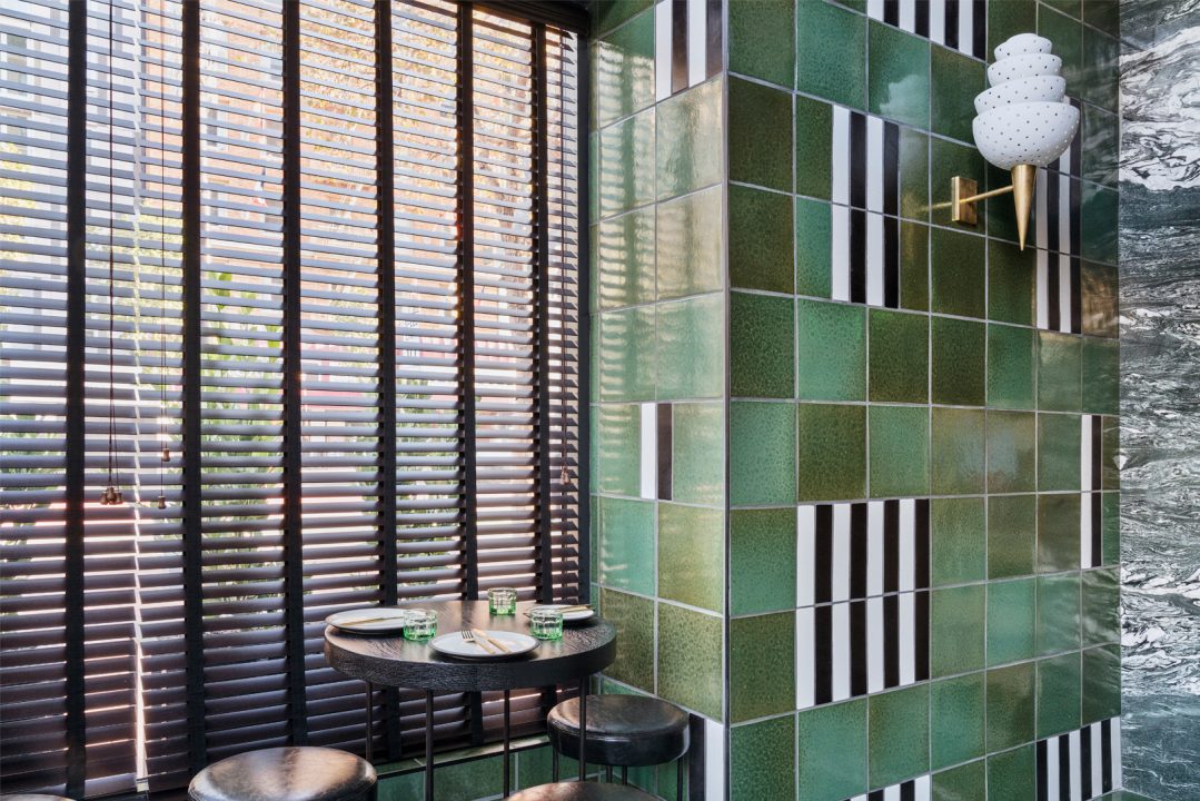 Stylish restaurant seating area with green tiled walls and natural light windows