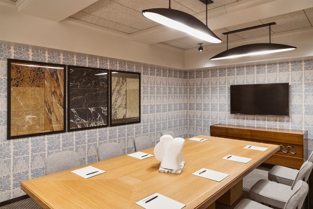 Private hotel boardroom with conference table, patterned walls, and mounted presentation screen