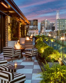 charmaines outdoor rooftop at night with firepits and view of the city skyline