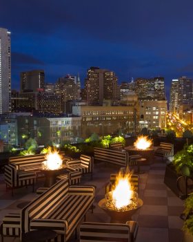 charmaines outdoor rooftop at night with firepits and view of the city skyline