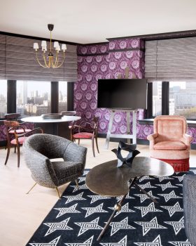 Stylish hotel suite with patterned wallpaper, lounge seating, and city view windows