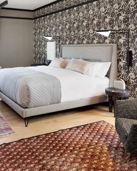 Spacious luxury hotel suite with floral wallpaper, king bed, and city views