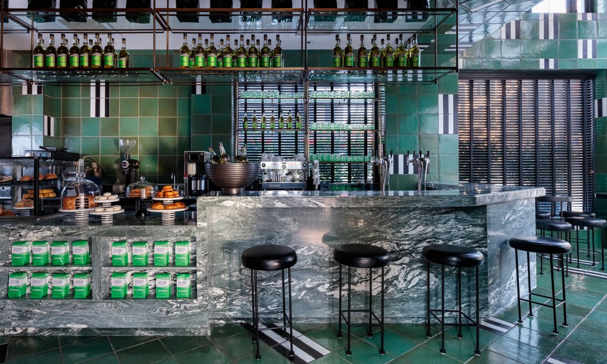 Modern café bar with marble counter, green tile interior, and bakery display
