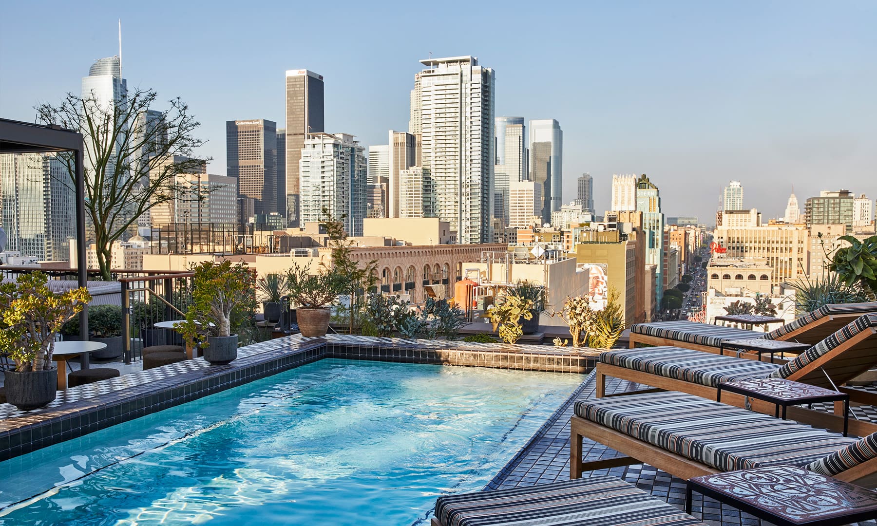 Rooftop Pool Deck with lounge chairs and view of downtown los angeles city skyline