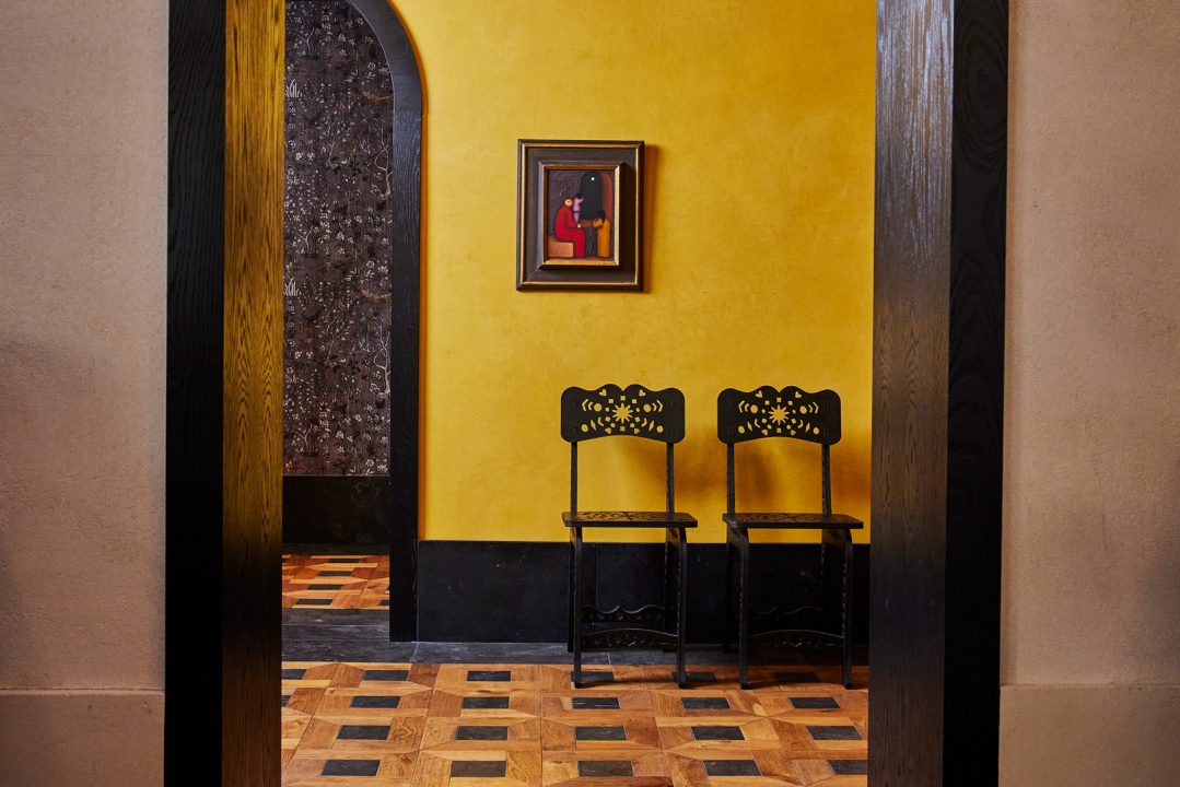 Art filled hotel interior with decorative chairs and warm yellow accent wall